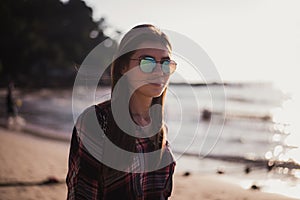 Young stylish happy hipster woman traveling around the world wearing aviator sunglasses, denim shirt, tropical island