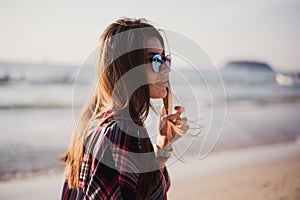 Young stylish happy hipster woman traveling around the world wearing aviator sunglasses, denim shirt, tropical island
