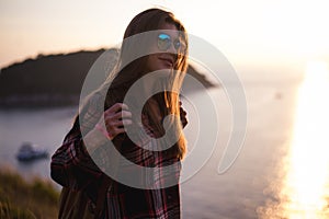 Young stylish hipster girl enjoy sunset on viewpoint. Travel woman with backpack