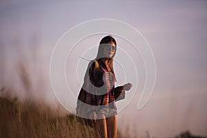 Young stylish hipster girl enjoy sunset on viewpoint. Travel woman with backpack