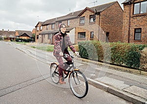 Young stylish hipster man riding on city Bicycle on the road of suburbs area among houses. Student on way to college on