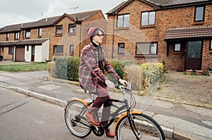 Young stylish hipster man riding on city Bicycle on the road of suburbs area among houses. Student on way to college on