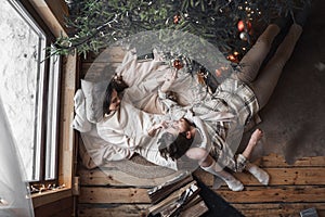 Young stylish love couple girl, guy lie on skin on floor in cozy wooden country house,chalet in winter forest