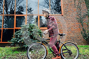 Young stylish man in helmet riding on cruiser city Bicycle on urban sidewalk to the office. Student on way to college on