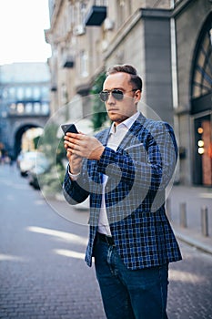 Young stylish man holding a mobile phone in the city center