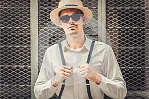 Young stylish man model in hat posing near the cell wall. Fashion shot