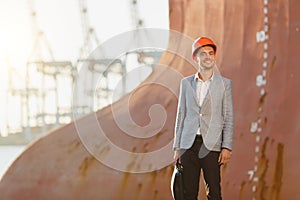 A young stylish man in a protective helmet against the backdrop of a seaport