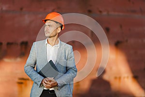 A young stylish man in a protective helmet against the backdrop of a seaport