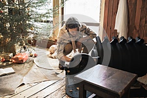 Young stylish man is stoking stove.Celebrating new year eve in cozy wooden country house in winter forest.Gifts,family