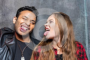 Young stylish man and woman sticking tongues out