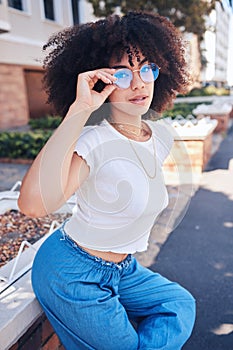 Young stylish mixed race woman with curly natural afro hair wearing trendy glasses outside. One female only looking