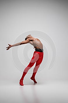 Young and stylish modern ballet dancer on gray background