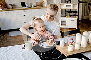 A young and stylish mother feeds her little daughter dessert.