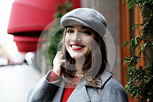 Young stylish pretty woman wearing red dress, grey coat and hat