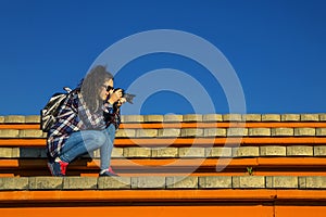 Young and stylish woman with camera sitting on the bench.