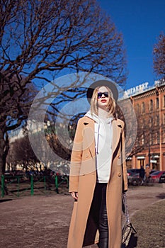 Young stylish woman in hat and coat. Trending girl on a walk