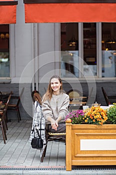 Young stylish woman having a french breakfast with coffee and cake sitting at the cafe terrace