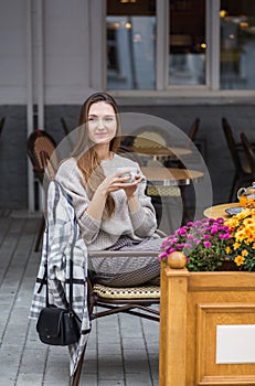 Young stylish woman having a french breakfast with coffee and cake sitting at the cafe terrace