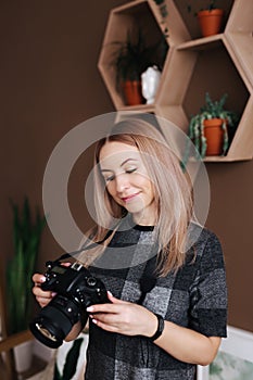Young stylish woman photographer checking photos on a camera in studio