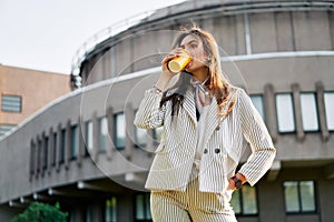 Young stylish woman in the street drinking morning coffee in sunshine light