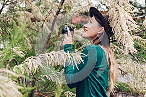 Young stylish woman taking photos using compact camera in summer garden. Girl enjoying hobby in park