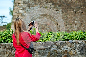 Young stylish woman tourist making photo of old castle. Girl having fun in the city in Europe