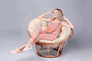 Young stylish woman with trendy shoes sitting in papasan chair