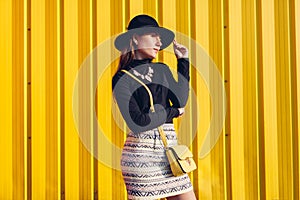 Young stylish woman wearing beautiful outfit with handbag and hat. Spring female clothes and accessories. Fashion