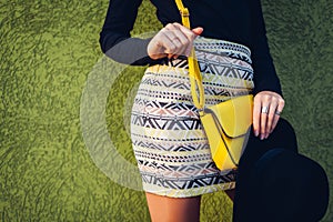 Young stylish woman wearing beautiful outfit with handbag and hat. Spring female clothes and accessories. Fashion