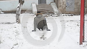 Young stylishly dressed man while walking in the Park in winter slipped and lost his balance