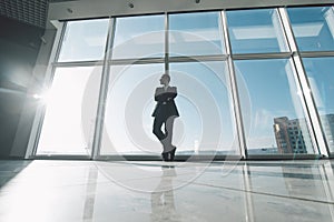 Young success business man standing satisfy against panoramic windows