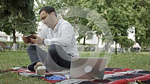 Young success businessman using tablet, laptop, mobile phone in the park