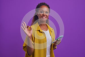 Young successful African American woman with phone in hand makes OK gesture