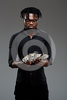 Young successful african businessman holding money over dark background.