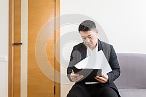 Young successful Asian man, waiting for a job interview, in the waiting room of the office center, sitting on a chair