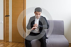 Young successful Asian man, waiting for a job interview, in the waiting room of the office center, sitting on a chair near the