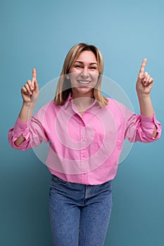 young successful blond careerist leader woman in a pink blouse shows her hands towards the empty space for advertising