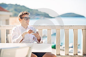 Young successful business man enjoying espresso coffee beverage in sunny marine panoramic cafe.