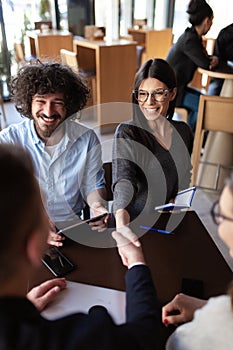 Young successful business people having a meeting at a cafe. Smiling and shaking hands