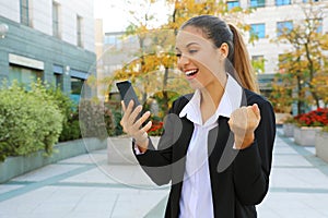 Young successful business woman holding smart phone outdoors