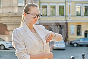 Young successful business woman looking at her wristwatch