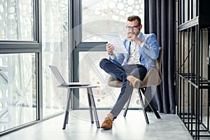 Young successful businessman analyzes financial document in his hand and drinks fragrant coffee in specially designated