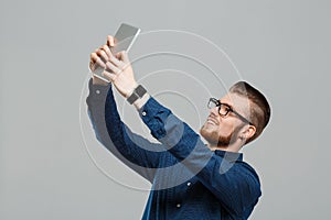 Young successful businessman looking at tablet over grey background.