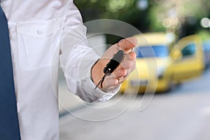 Young successful businessman offering a car key. Close-up of driver's hand showing key