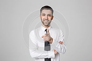 Young successful businessman pointing direction with finger over dark grey background. Copy space.