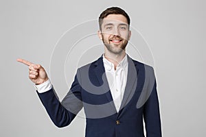 Young successful businessman pointing direction with finger over dark grey background. Copy space.