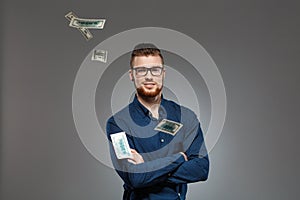 Young successful businessman posing among falling money over dark background.