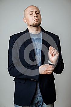 Young successful businessman posing, fastening jacket over beige background.