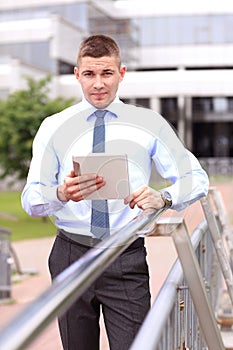 Young successful businessman with tablet outdoors