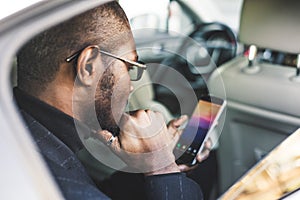 Young successful businessman talking on the phone sitting in the backseat of a expensive car. Negotiations and business